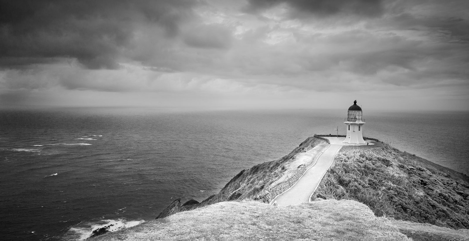 Leuchtturm auf einer Klippe über dem Meer, Schwarzweiß, Neuseeland